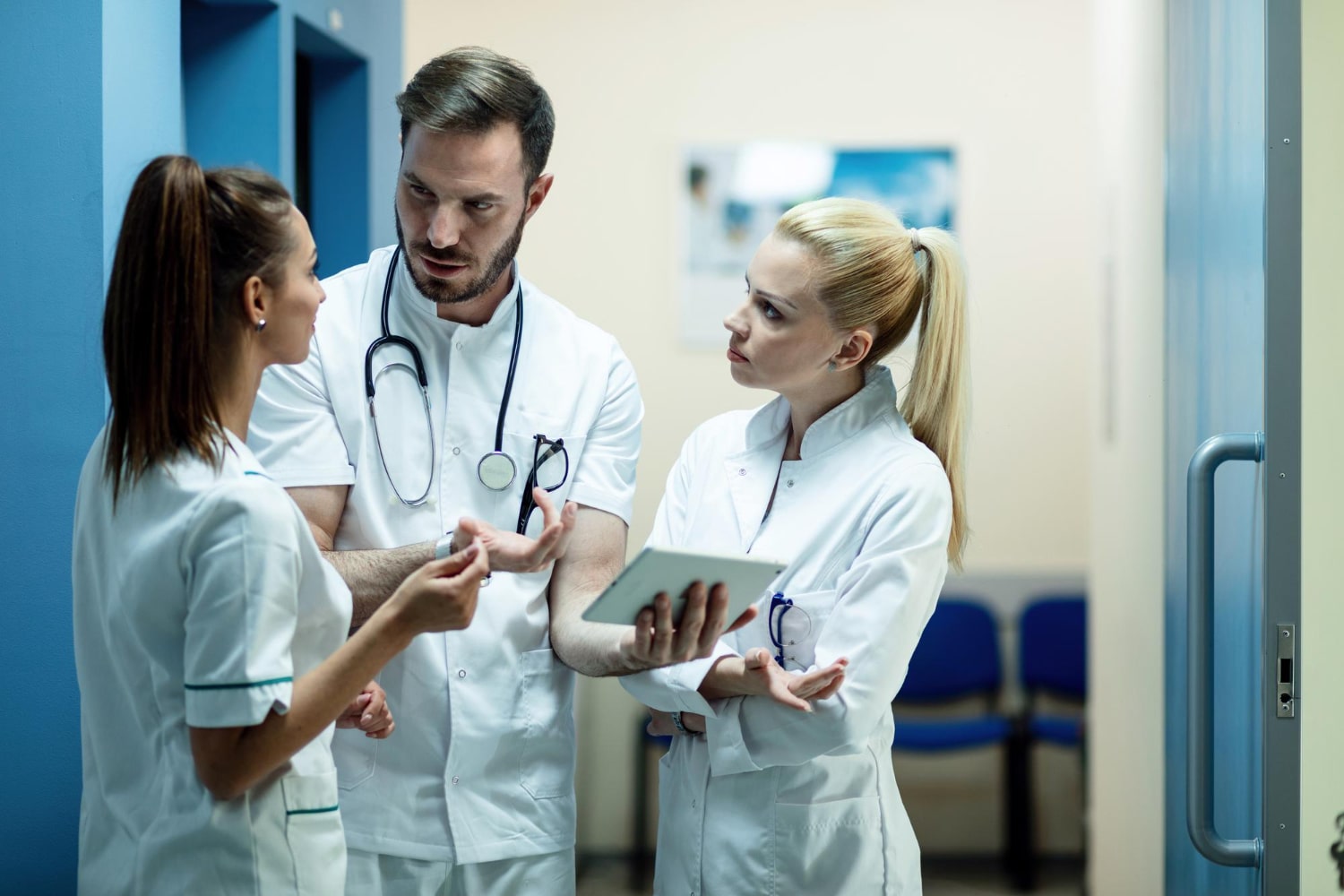 team-doctors-going-through-electronic-medical-reports-touchpad-talking-hallway-clinic-min